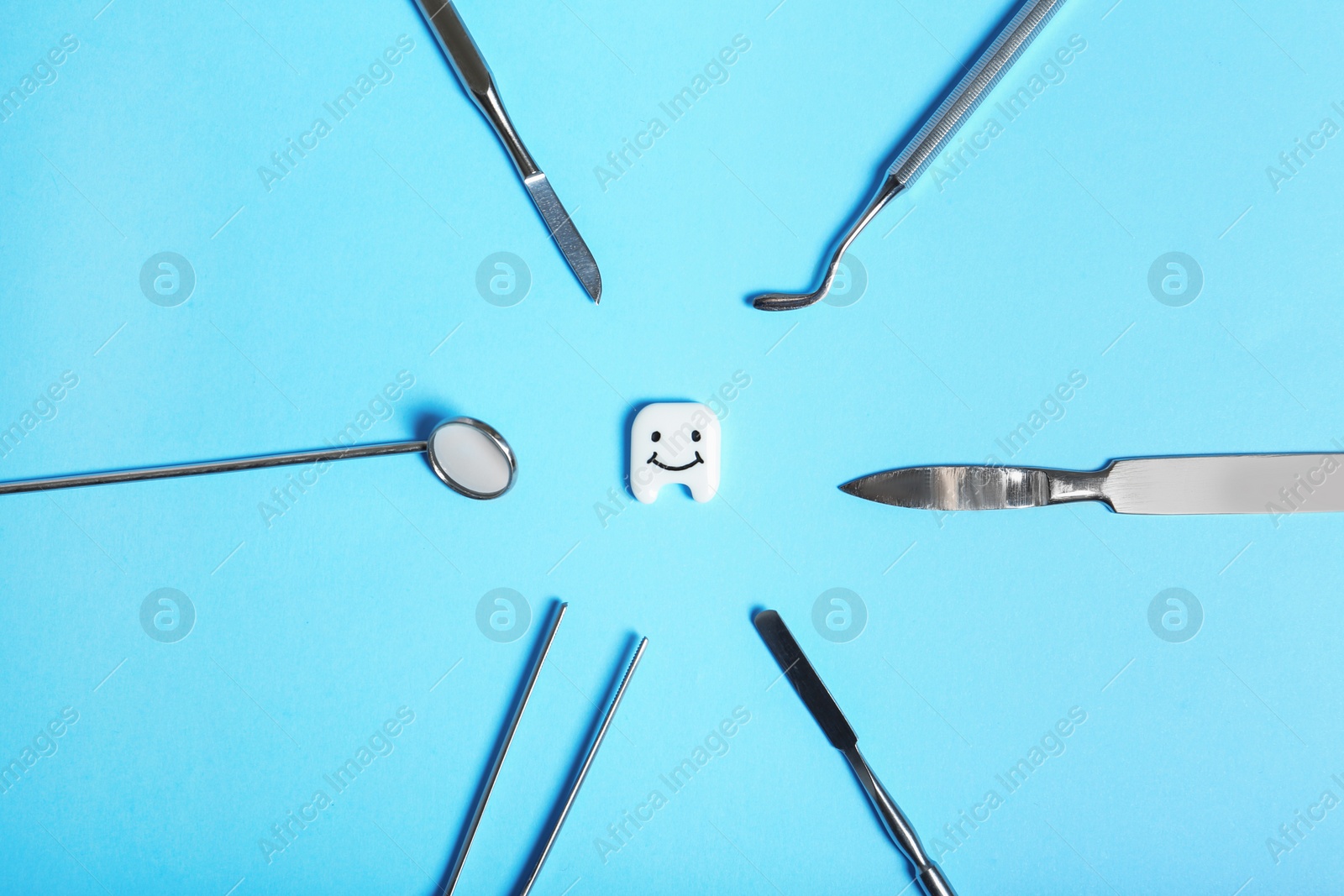 Photo of Flat lay composition with professional dental tools and small plastic tooth on color background