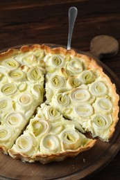Board with tasty leek pie and cake server on wooden table, closeup