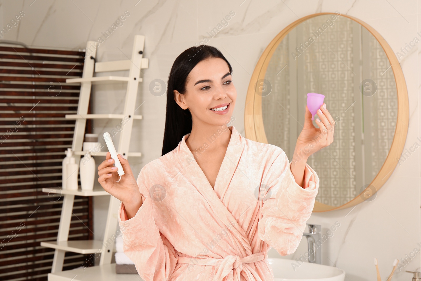 Photo of Young woman with menstrual cup and tampon in bathroom