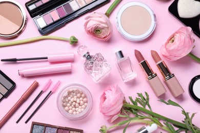 Flat lay composition with different makeup products and beautiful spring flowers on pink background