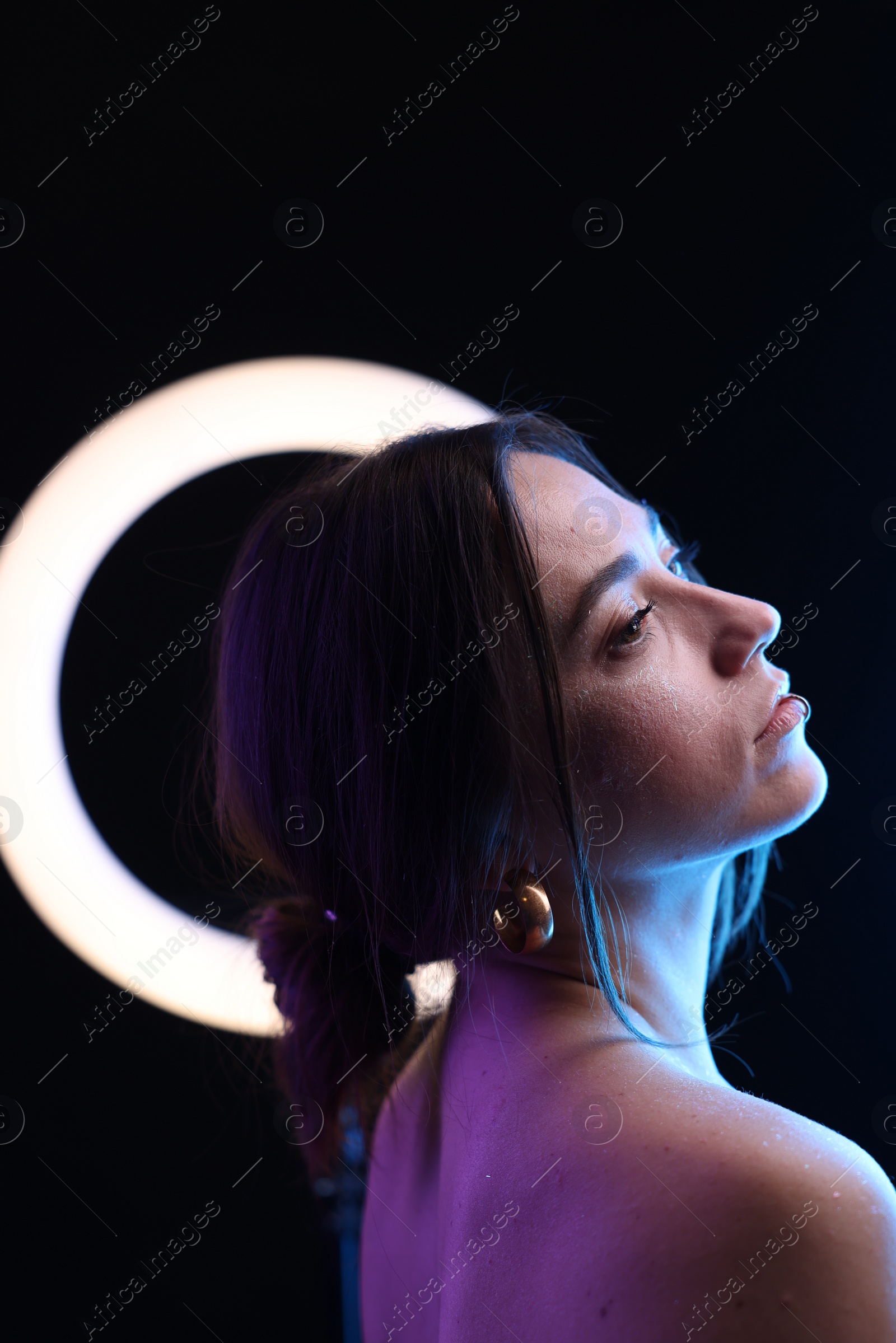 Photo of Beautiful woman and ring lamp on dark background in neon lights