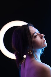 Beautiful woman and ring lamp on dark background in neon lights