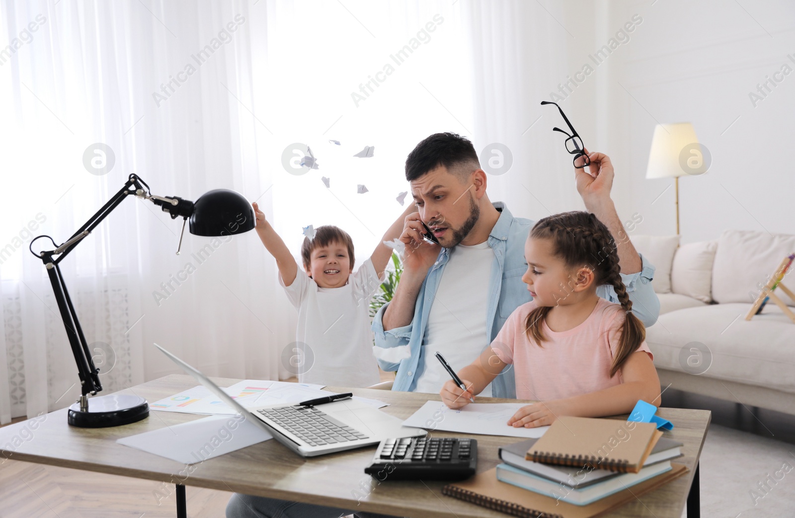 Photo of Overwhelmed man combining parenting and work at home