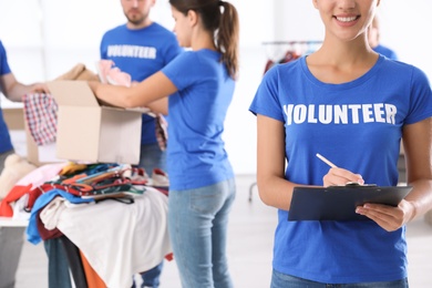 Photo of Female volunteer with clipboard listing donations indoors