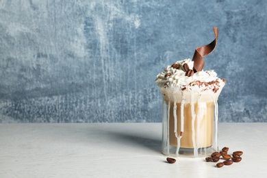 Photo of Glass cup of tasty coffee with whipped cream and chocolate on table against color background. Space for text