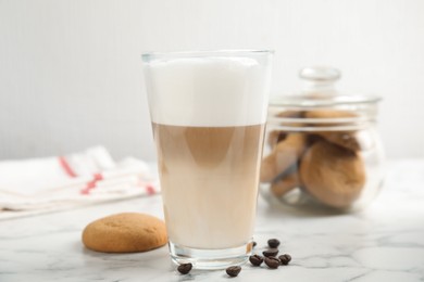 Photo of Delicious latte macchiato, cookies and coffee beans on white marble table