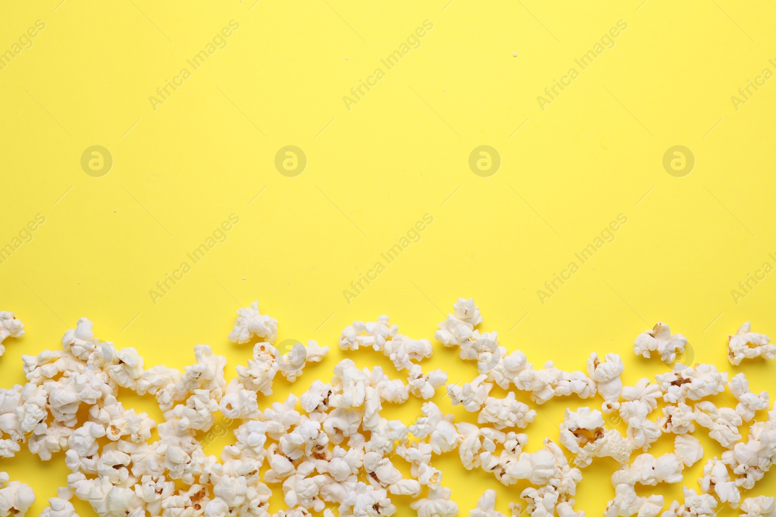 Photo of Tasty pop corn on yellow background, flat lay. Space for text