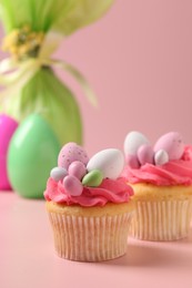 Photo of Tasty decorated Easter cupcakes on pink background, selective focus