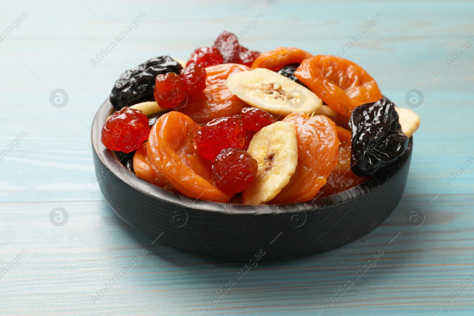 Photo of Mix of delicious dried fruits on light blue wooden table