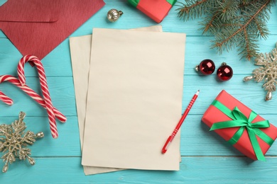 Photo of Flat lay composition with blank sheets of paper and Christmas decorations on turquoise wooden table, space for text. Writing letter to Santa