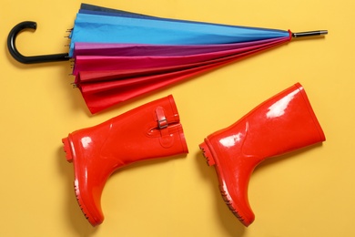 Flat lay composition with umbrella and rubber boots on color background