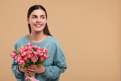 Photo of Happy young woman with beautiful bouquet on beige background. Space for text