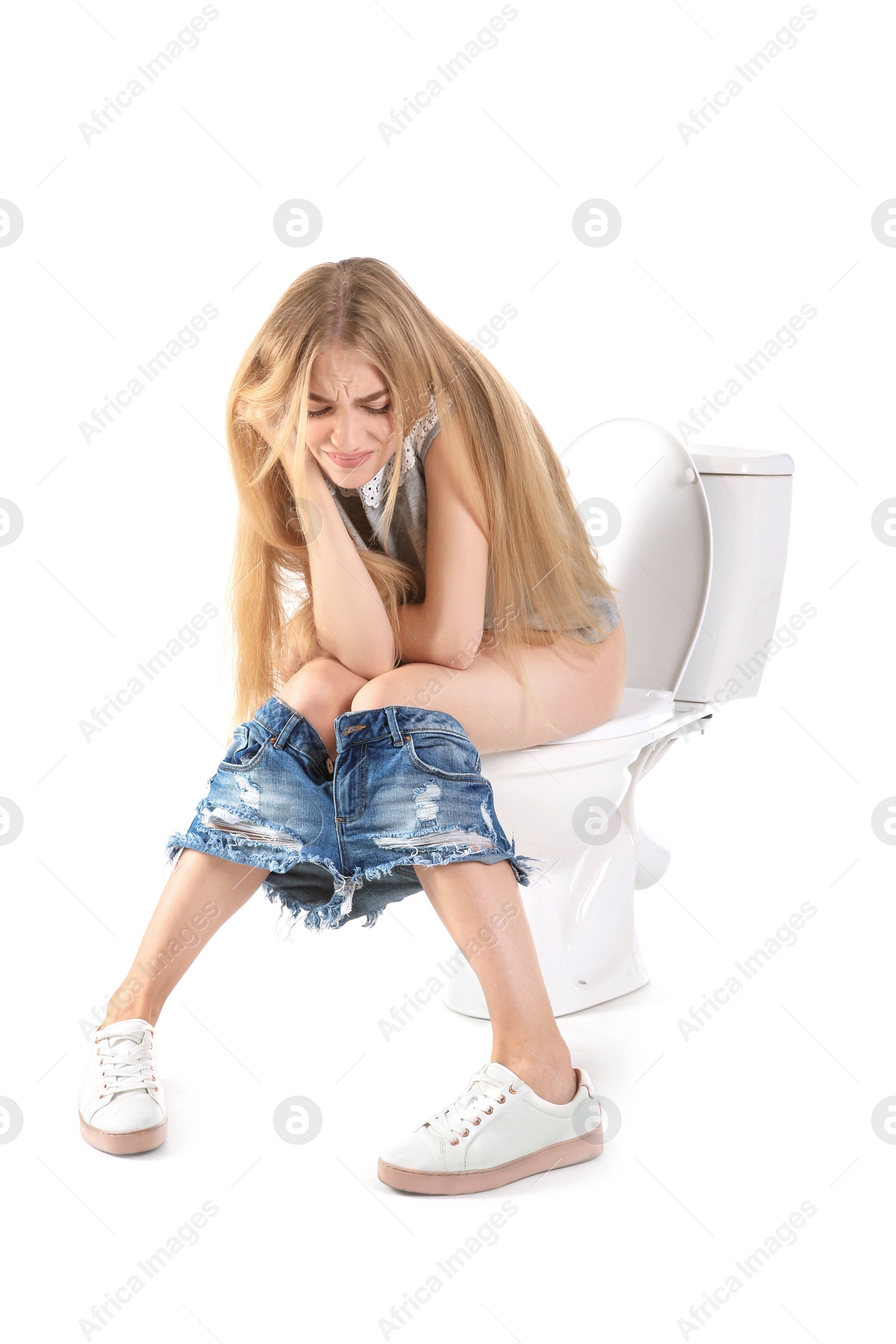 Photo of Young woman suffering from diarrhea on toilet bowl. Isolated on white