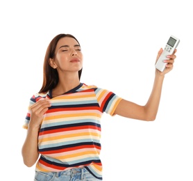 Photo of Young woman with air conditioner remote suffering from heat on white background