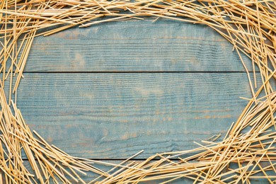 Photo of Frame of dried hay on light blue wooden background, flat lay. Space for text