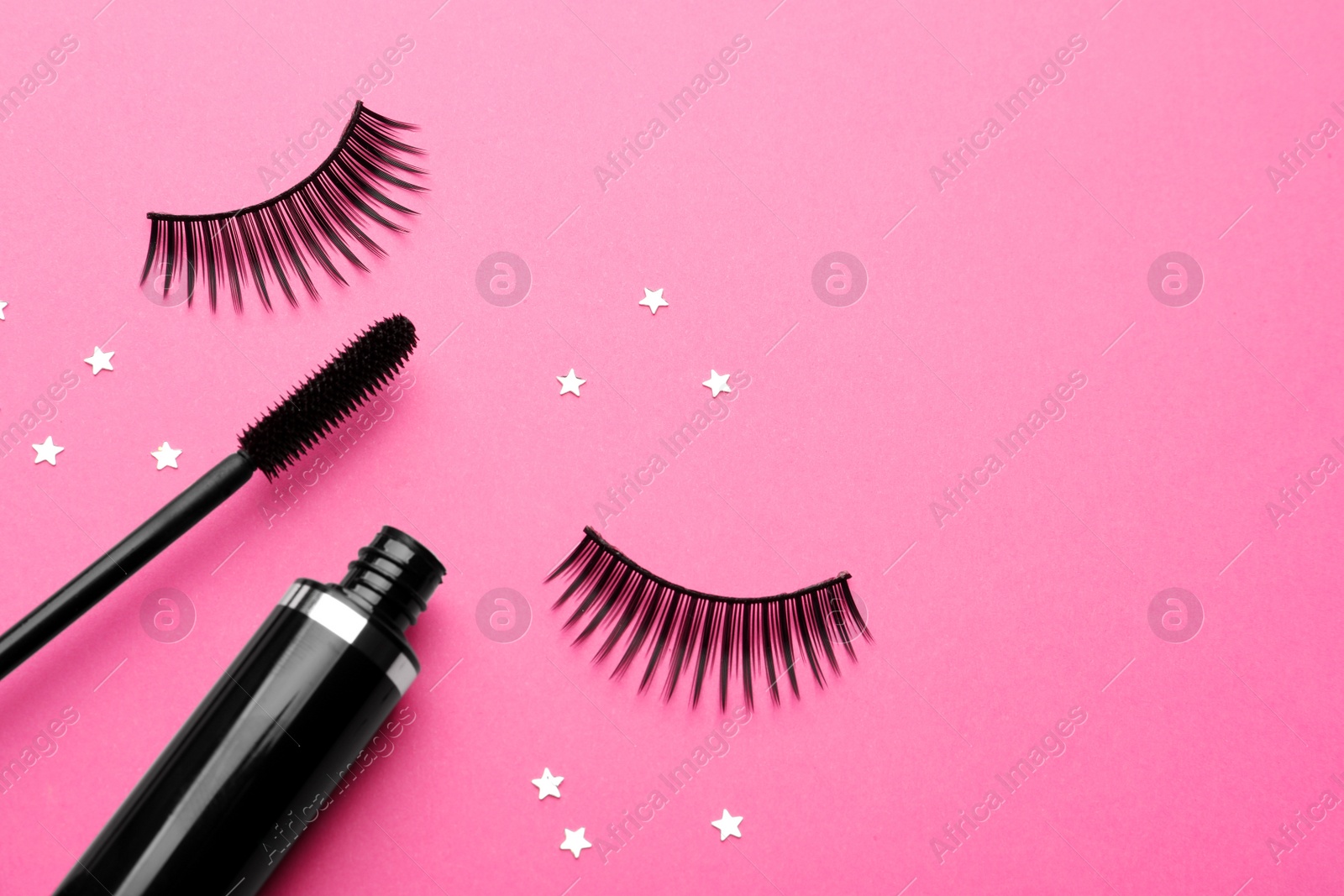 Photo of False eyelashes and mascara on pink background, flat lay. Space for text