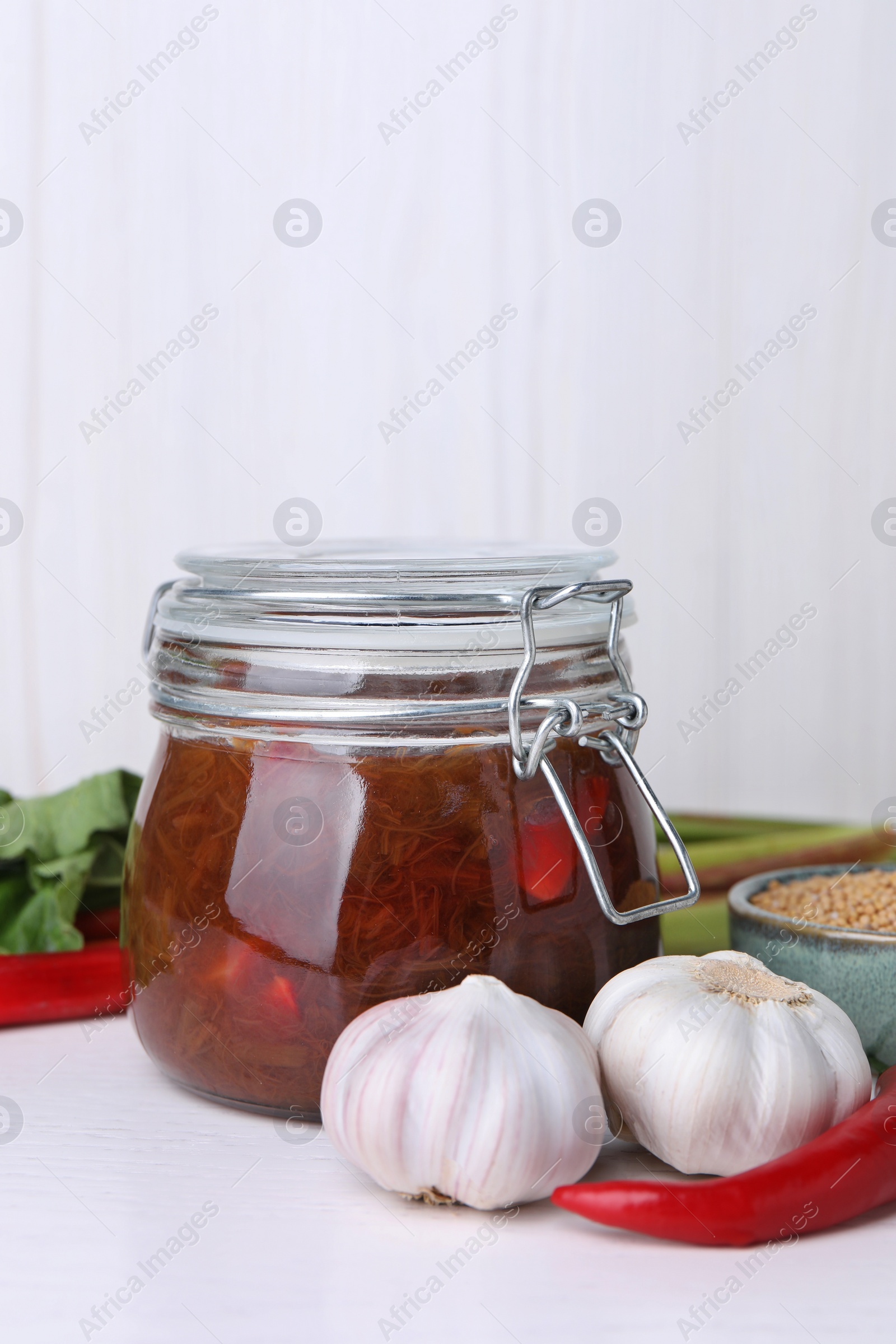 Photo of Tasty rhubarb sauce and ingredients on white table, space for text