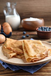 Photo of Delicious crepes served on wooden table, closeup. Space for text