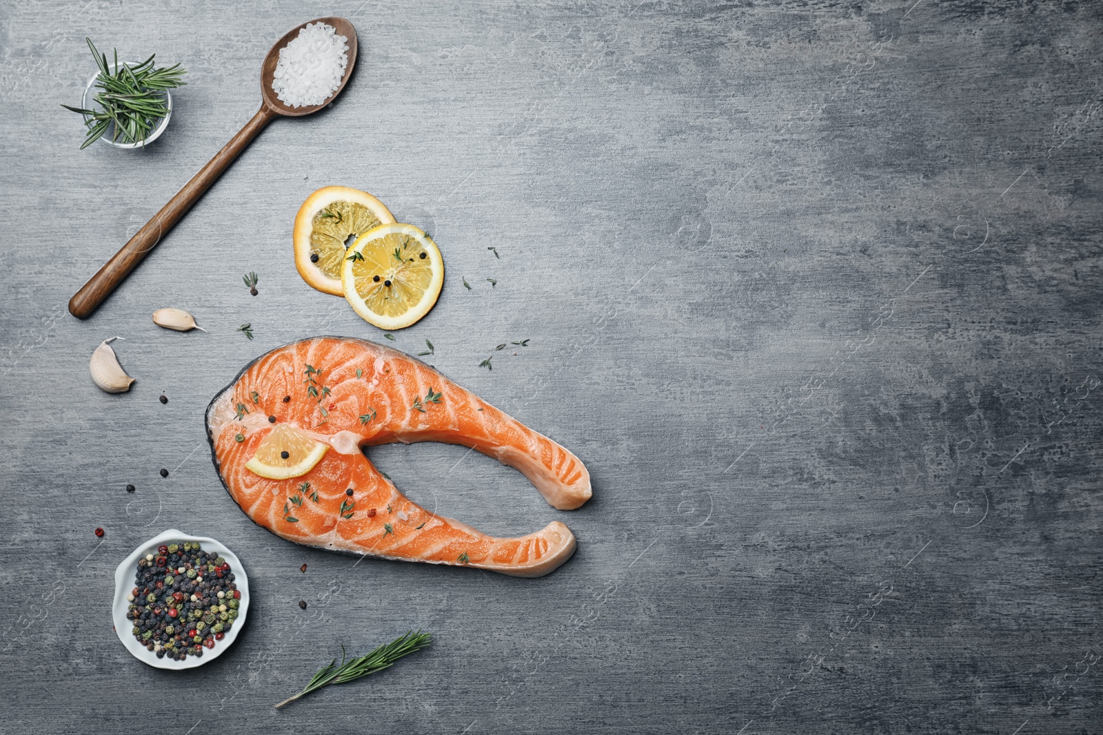 Photo of Fresh raw salmon steak with seasonings on gray background, top view