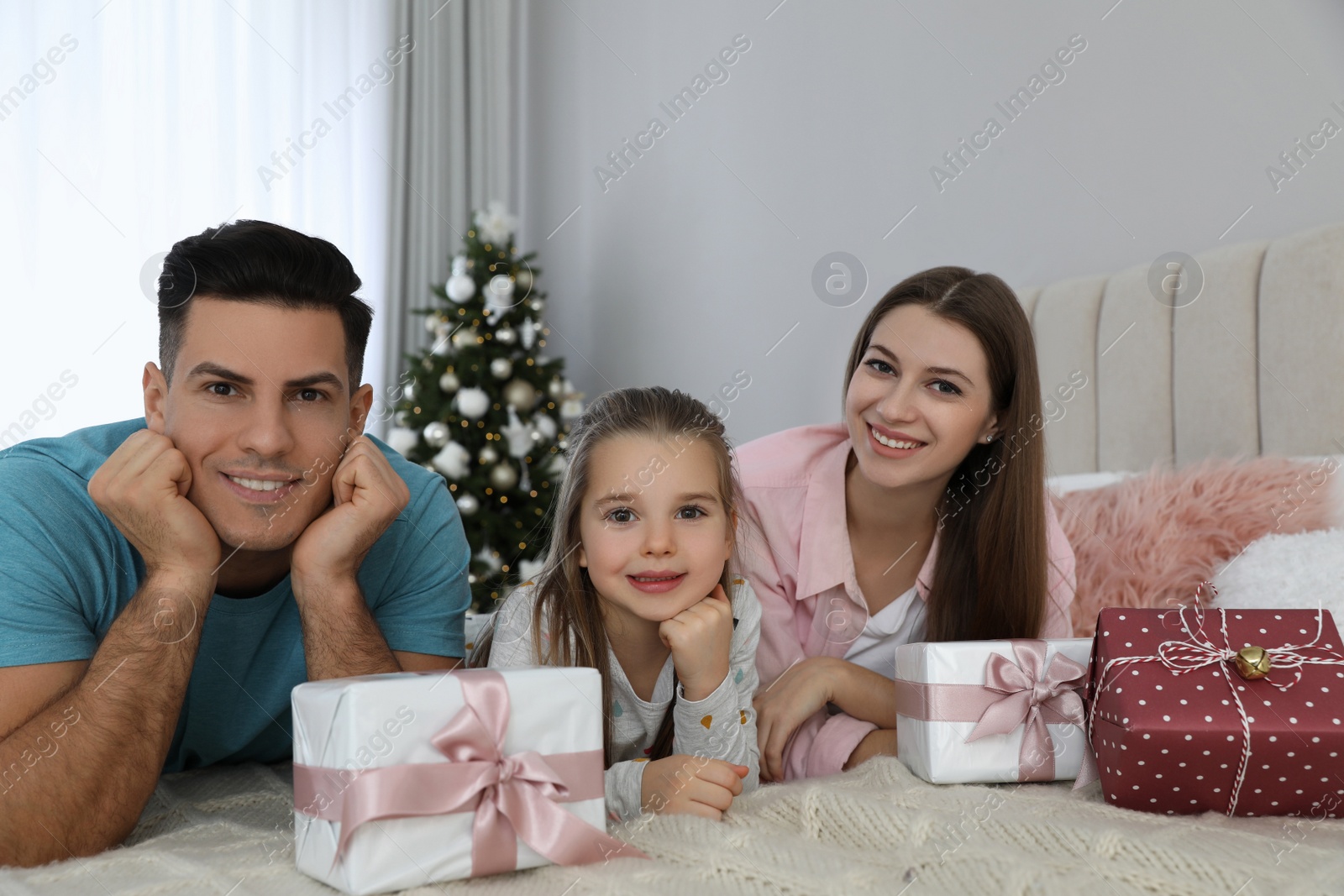 Photo of Portrait of happy family with Christmas gifts on bed at home