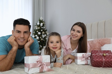 Portrait of happy family with Christmas gifts on bed at home