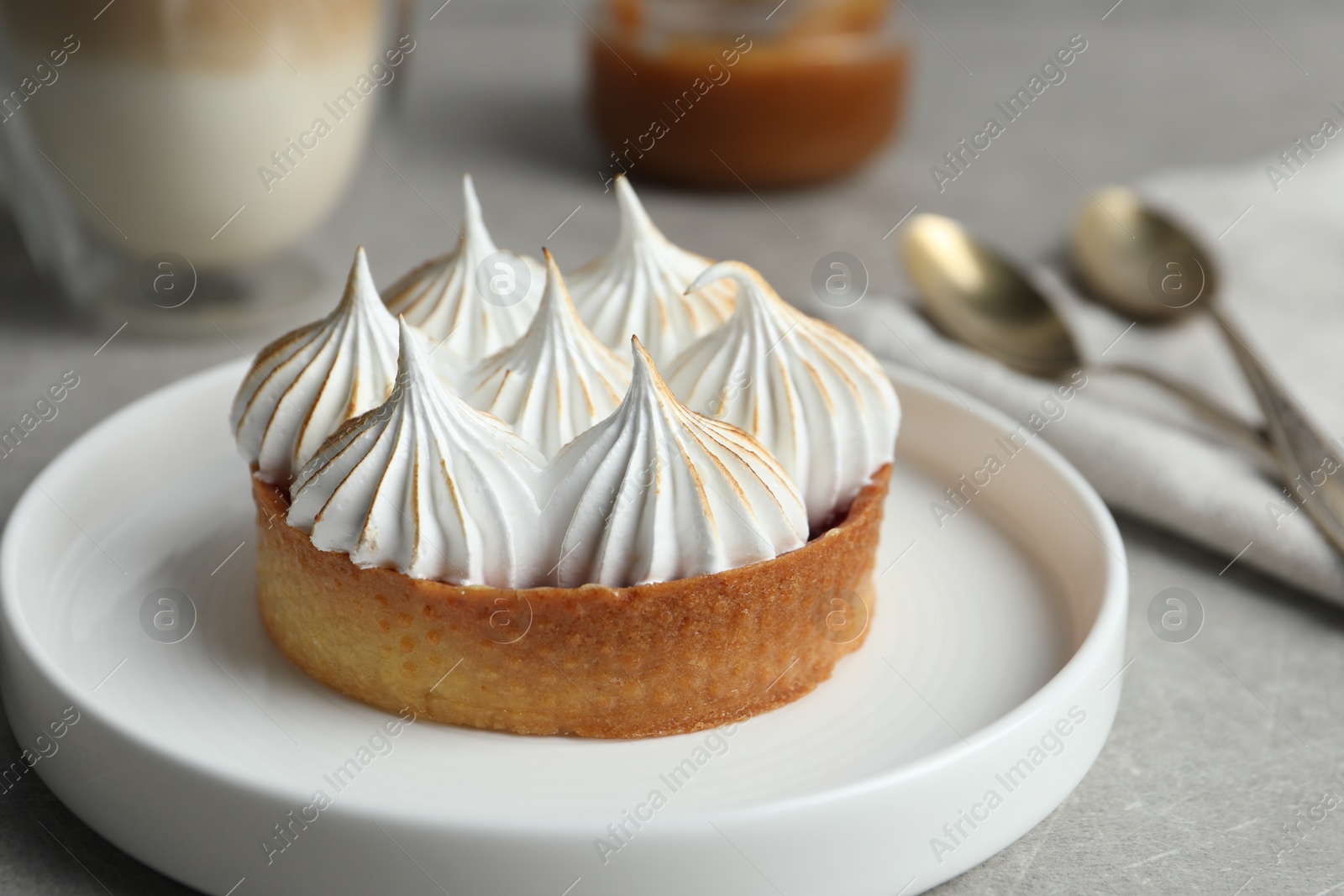 Photo of Tartlet with meringue on grey table, closeup. Delicious dessert