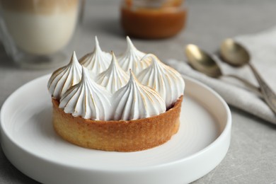 Tartlet with meringue on grey table, closeup. Delicious dessert