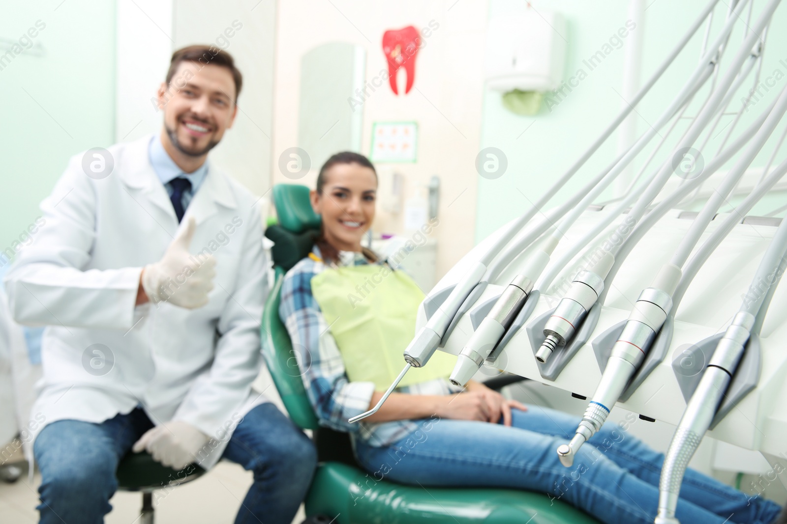 Photo of Professional dentist's equipment and blurred doctor with patient on background