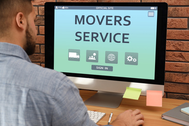 Image of Young man using computer to order movers service in office, closeup
