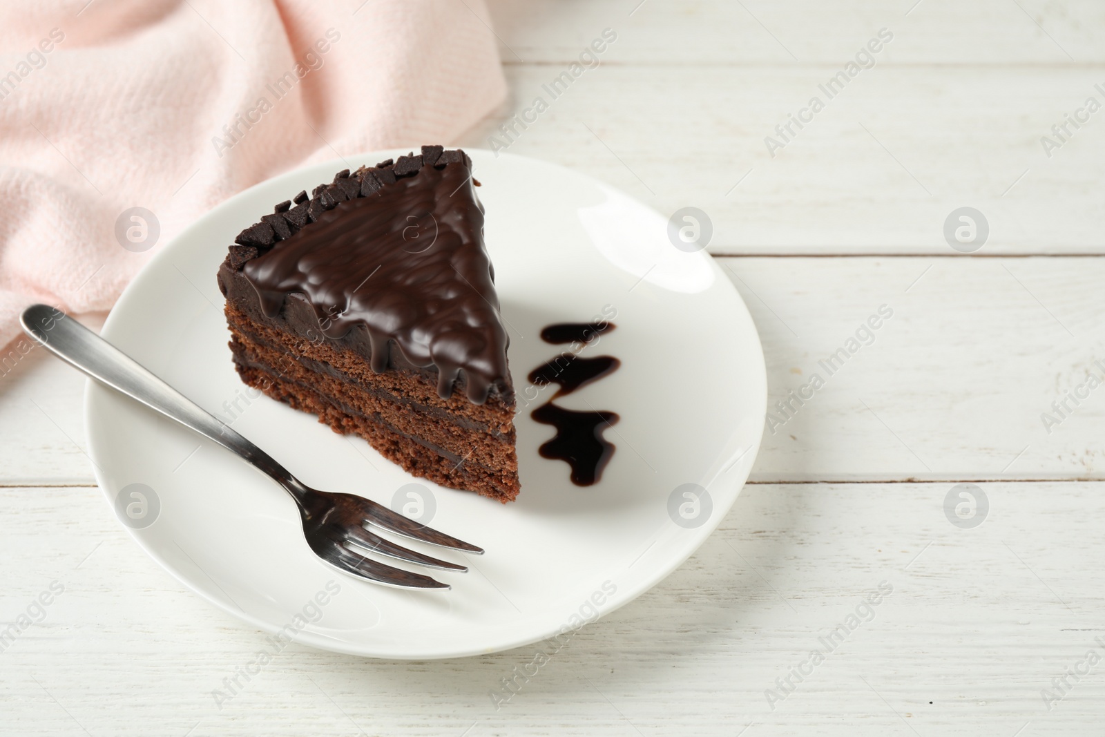 Photo of Tasty chocolate cake served on white wooden table. Space for text