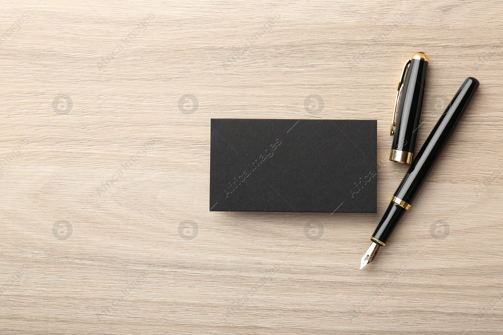 Photo of Blank black business card and fountain pen on wooden table, flat lay. Mockup for design