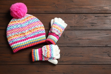 Warm knitted hat and mittens on wooden background, flat lay. Space for text