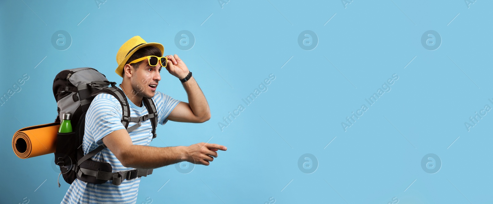 Photo of Emotional male tourist with travel backpack on turquoise background