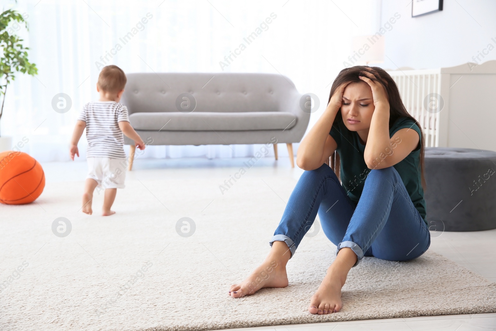 Photo of Young mother suffering from postnatal depression and little baby in room