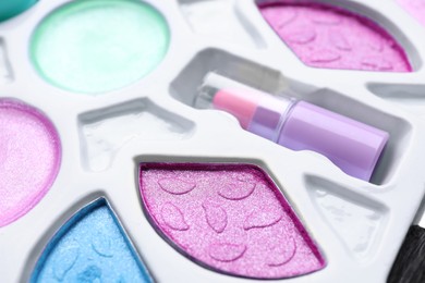 Photo of Decorative cosmetics for kids. Eye shadow palette with lipstick as background, closeup