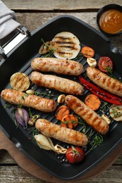 Tasty fresh grilled sausages with vegetables on wooden table, flat lay