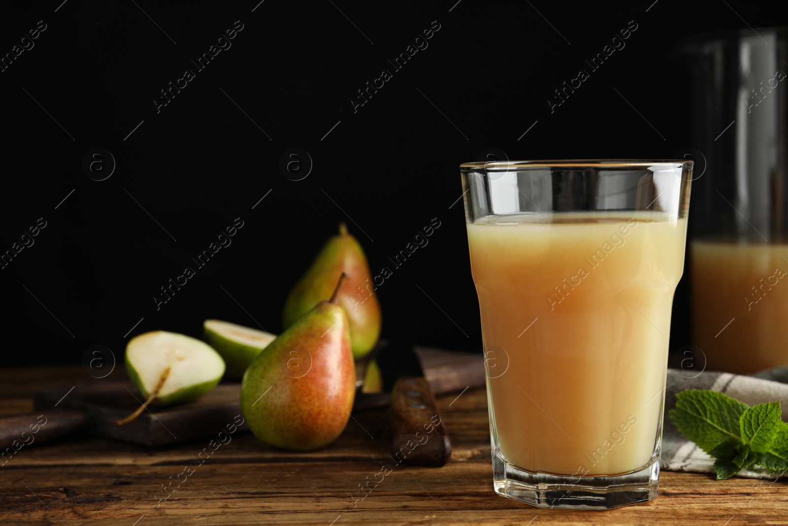 Photo of Fresh pear juice in glass on wooden table, closeup. Space for text