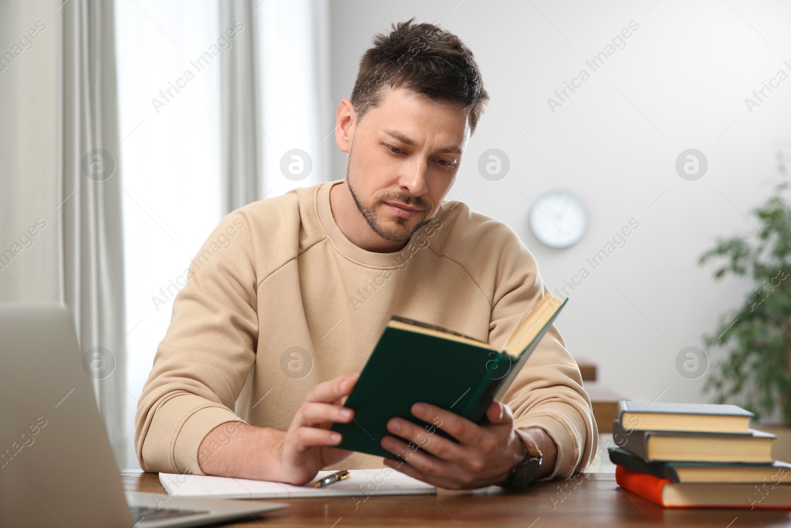 Photo of Man reading book at table in library