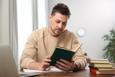 Man reading book at table in library