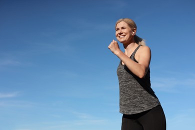 Photo of Woman listening to music while running outdoors in morning, low angle view. Space for text