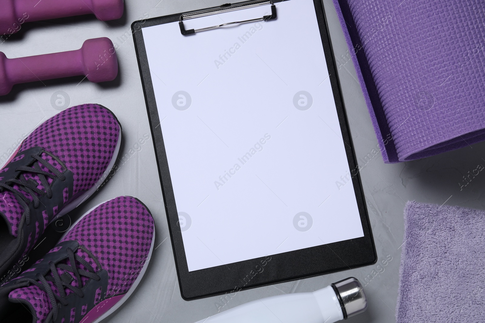 Photo of Clipboard with paper sheet, bottle and sports equipment on light gray background, flat lay. Personal training