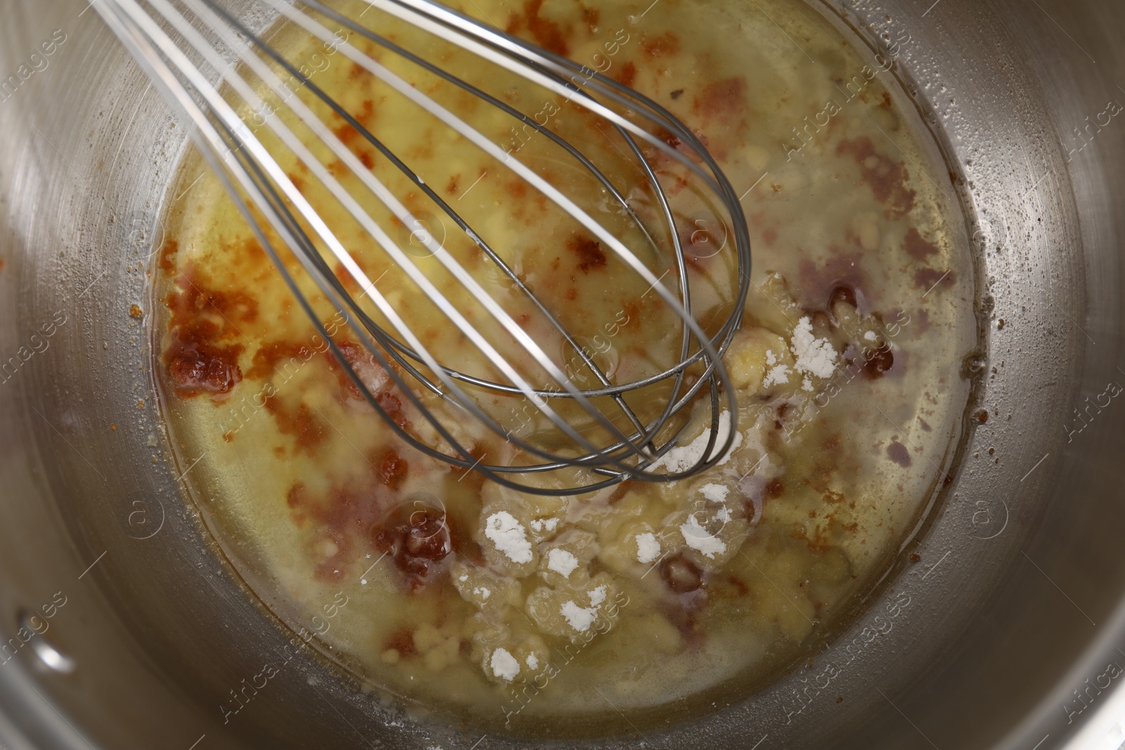 Photo of Cooking delicious turkey gravy. Mixing ingredients with whisk in pot, top view