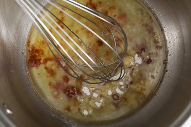 Photo of Cooking delicious turkey gravy. Mixing ingredients with whisk in pot, top view