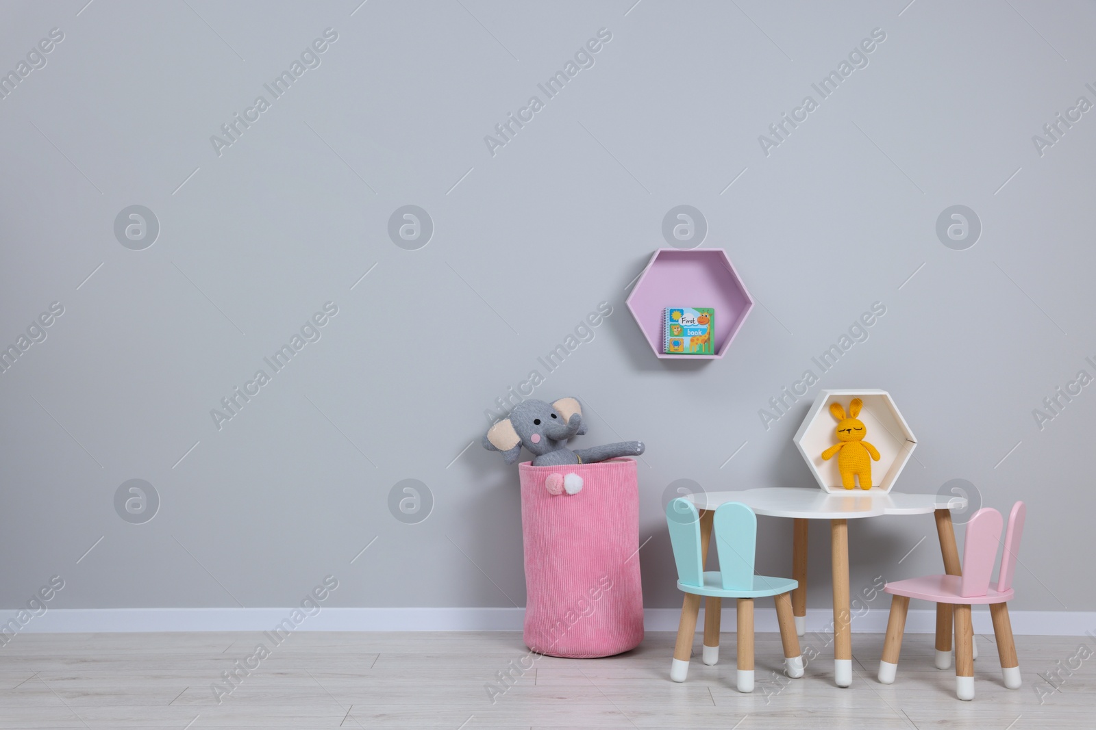 Photo of Kindergarten interior. Stylish furniture and toys near grey wall, space for text