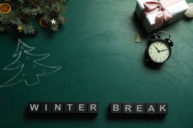 Photo of Black cubes with text Winter Break and Christmas decor on green background, flat lay. School holidays