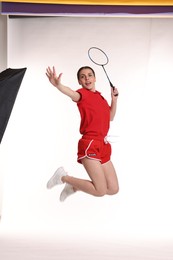 Photo of Young woman playing badminton with racket on white background