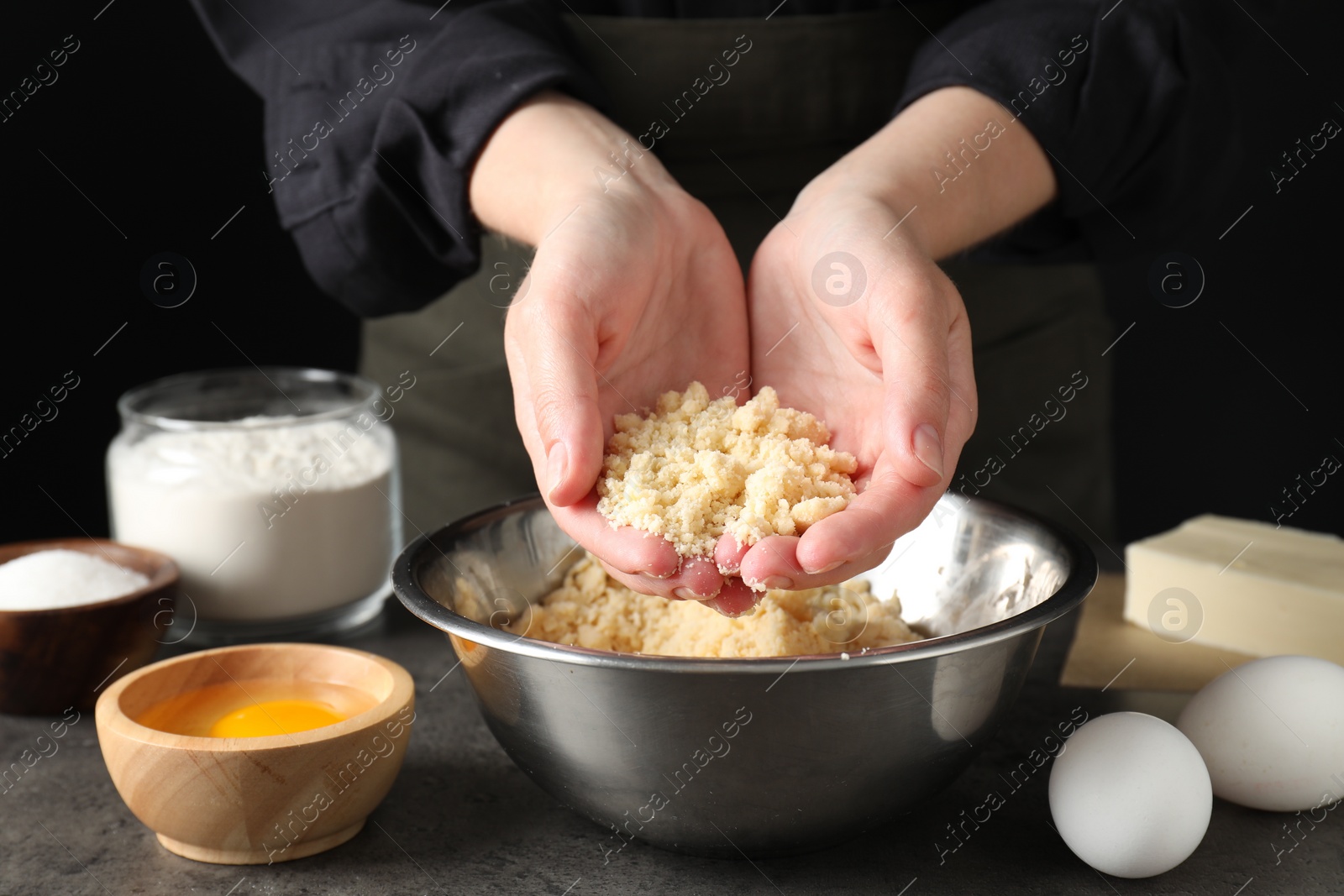 Photo of Woman with shortcrust pastry at grey table, closeup