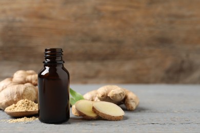Photo of Ginger essential oil in bottle on light grey table. Space for text