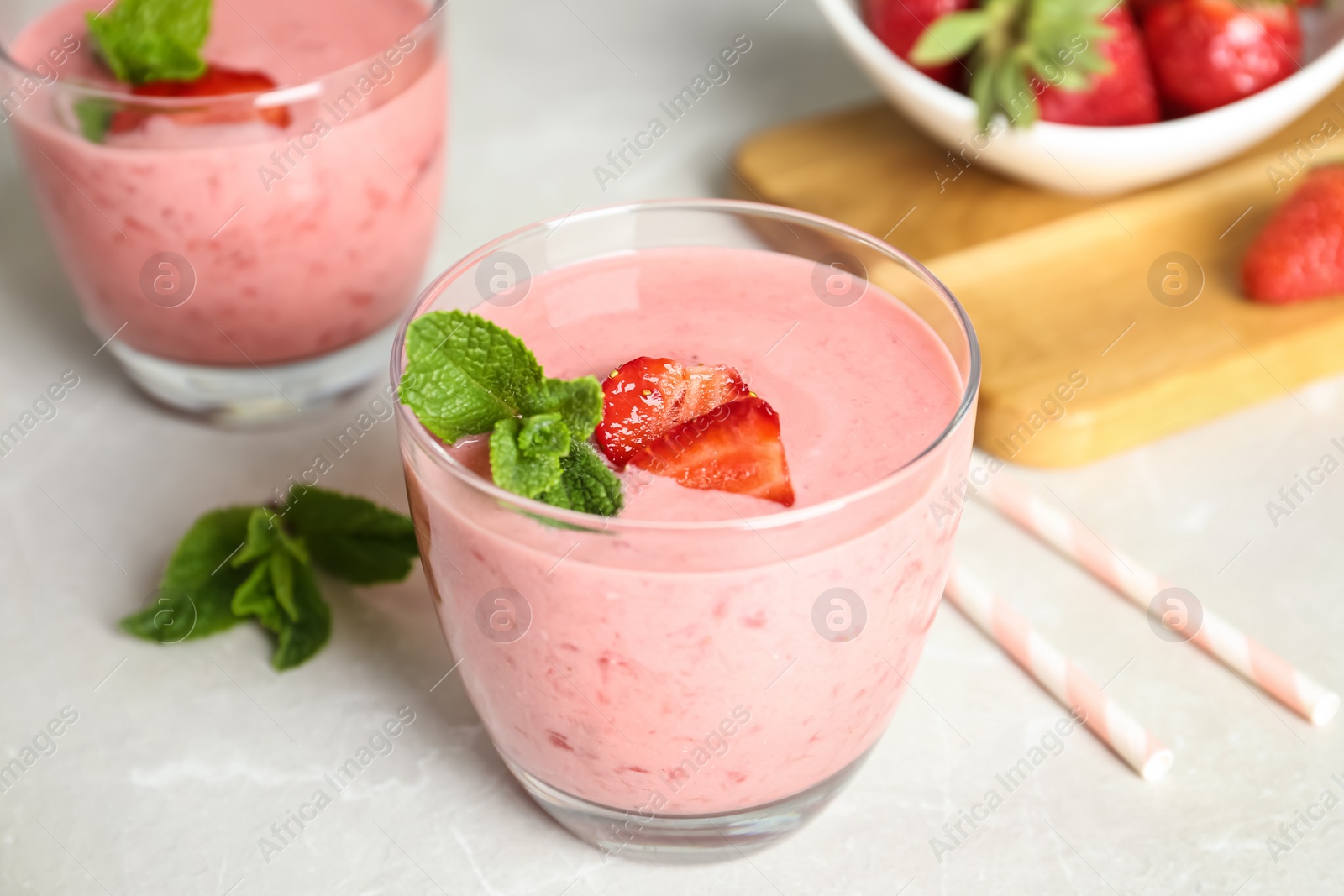 Photo of Tasty strawberry smoothie with mint in glass on light grey table