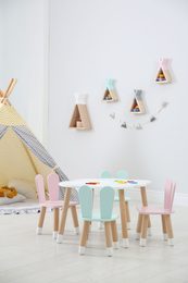 Photo of Cute children's room interior with teepee tent and little table